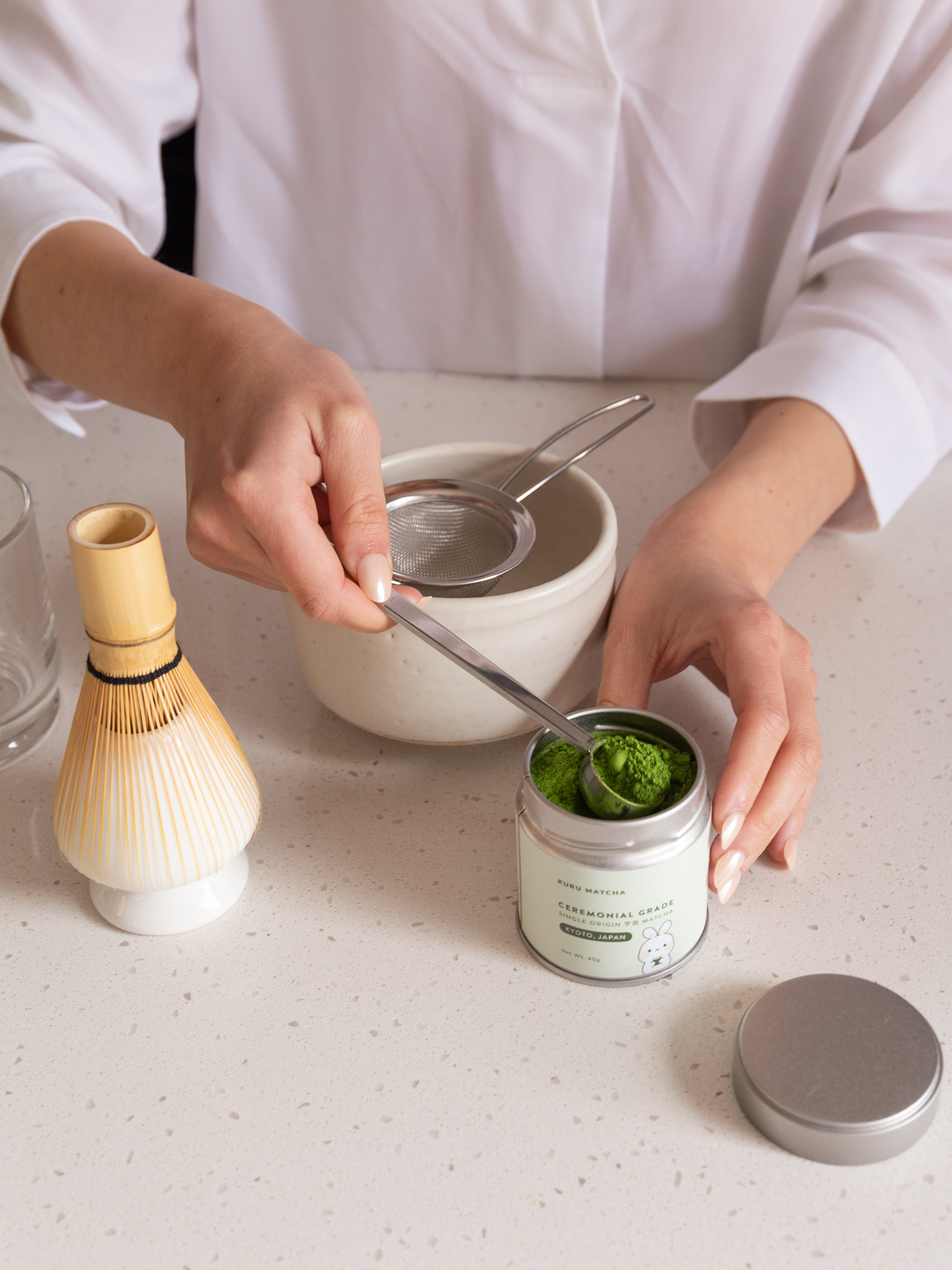 Person preparing matcha with vibrant green matcha powder and authentic Japanese tea ware, showcasing traditional tea-making methods